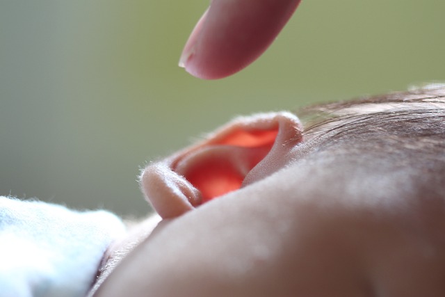 ett vuxet pekfinger strax ovanför en bebis öra